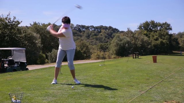 Attractive Mature woman playing Golf at the driver range.