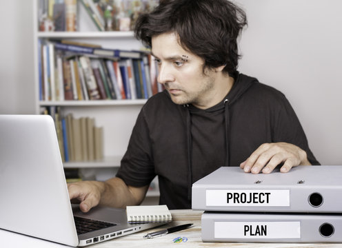 Project and Plan  - two folders on office desk. Man working on n