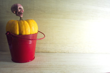 skull on the yellow pumpkin in red bucket