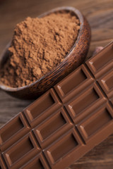 Chocolate bar, candy sweet, cacao beans and powder on wooden bac