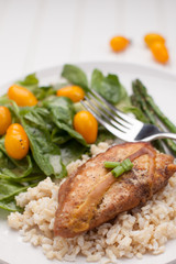 Dinner plate of lemon pepper mustard chicken with brown rice, Italian garden salad, and asparagus cooked in avocado oil on white vertical view