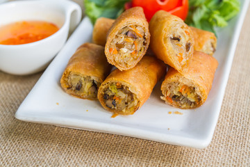 Deep fried spring rolls and sweet sauce on white plate.