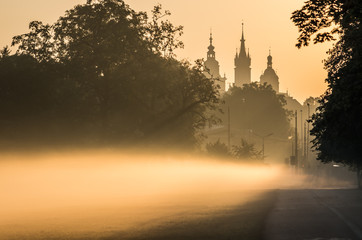 Misty Blonia meadow in Krakow, Poland, with St Mary's church and Town Hall towers in the background.