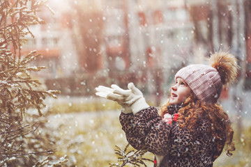 Little girl catches falling snowflakes.