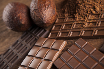 Chocolate bar, candy sweet, cacao beans and powder on wooden bac