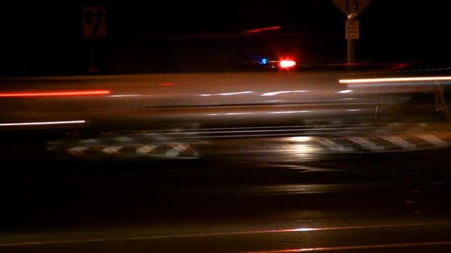 A police car guards a road block at a busy intersection. Slow shutter.HD 1080.