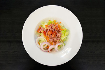 fresh ham salad in a white plate on black wooden background.