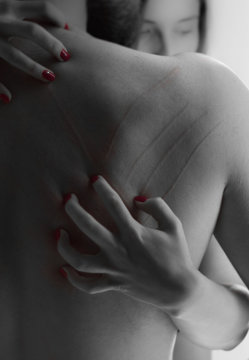 Woman's Hand Scratching Down Man's Bare Back - Black And Red