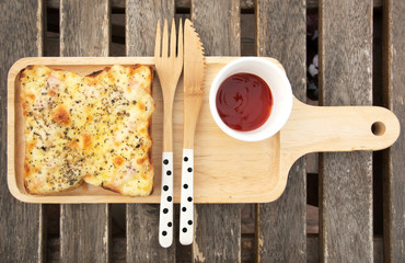 Rectangular  pizza with topping and sauce on a wooden table ,pizza on rectangular wooden tray ,pizza with knife and spoon.