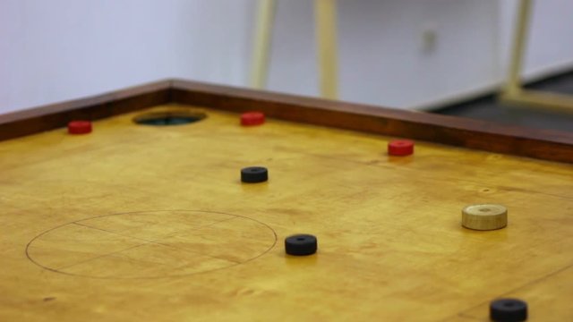 Two friends playing carrom game, strike and pocket table game, family tournament