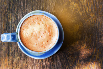 Hot milk tea with sunshine on wooden background.(Top view)