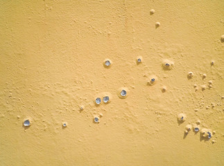 The background of concrete wall is painted roughly in yellow color 