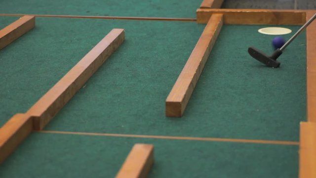 Persistent person trying to roll mini golf ball into hole, never give up concept