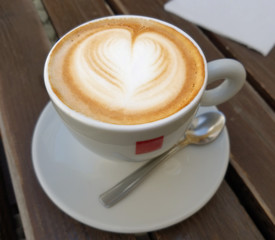 Delicious cappuccino coffee cup with froth heart design
