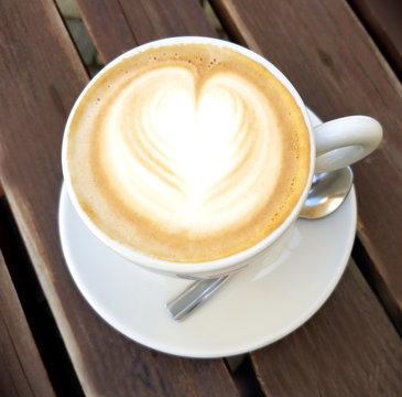 Delicious cappuccino coffee cup with froth heart design