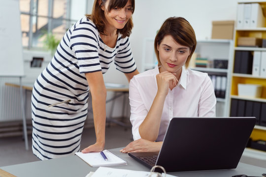 zwei frauen im büro schauen gemeinsam auf laptop