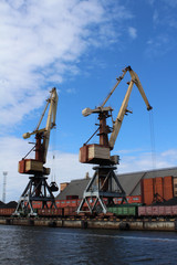 Fototapeta na wymiar Two yellow cargo container cranes in harbor