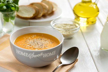 Pumpkin soup with sesame in a gray bowl on a table.