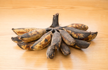 bunch of black overripe bananas on a wooden background