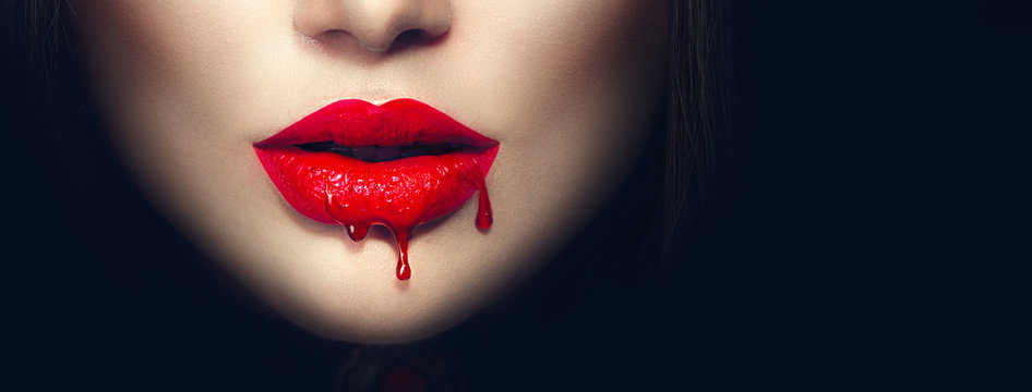 Sexy vampire red lips with dripping blood closeup isolated on black background