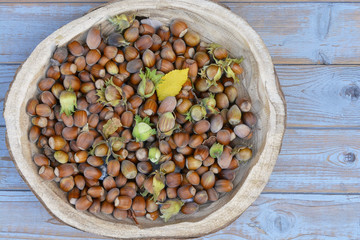 Close up of A wooden bowl with a lot of hazel chest nuts on a wooden background
