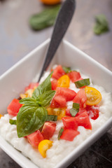 Cottage cheese with organic yellow and red tomatoes and basil macro shot