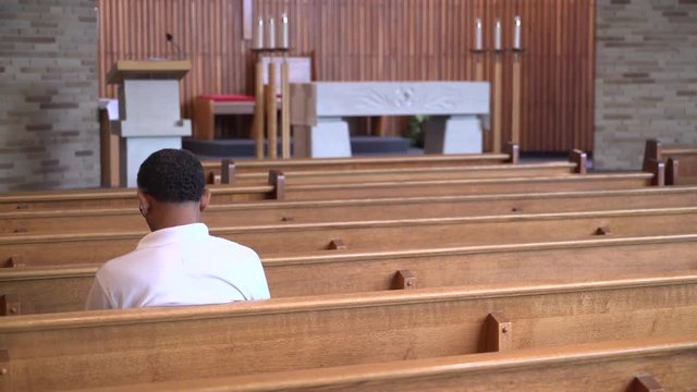 Man sits in an empty church praying
