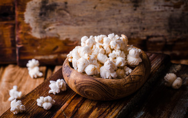 Wooden bowl full of sweet popcorn in wooden vintage bowl on rustic table. Vintage style. Selective focus
