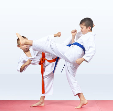 Two karateka beat kicks on the red mats