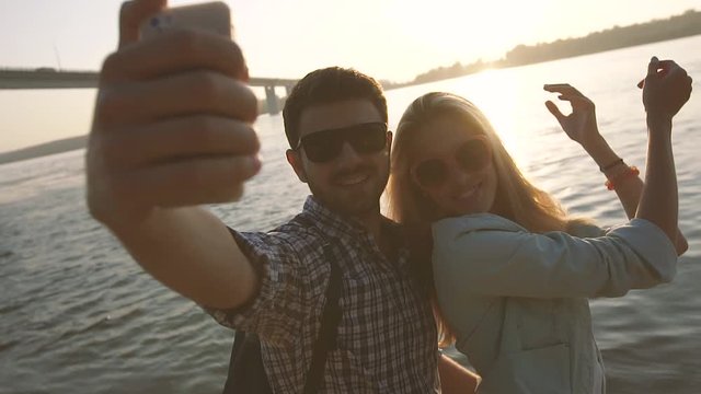 Happy couple in love taking selfie photo near the river on a wonderful evening