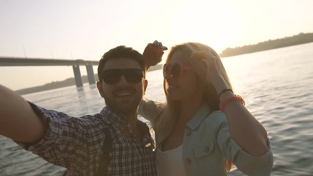 Joyful couple trying to take funny and beautiful photo of themselves