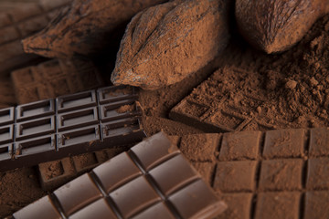 Chocolate bar, candy sweet, cacao beans and powder on wooden bac