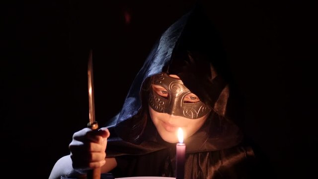 Satanic druid girl with a knife, book and candle. 4K UHD