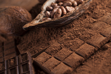 Dark homemade chocolate bars and cocoa pod on wooden
