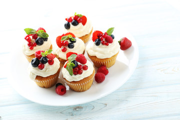 Tasty cupcakes with berries on white wooden table