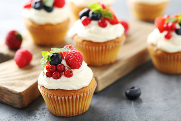 Tasty cupcakes with berries on cutting board