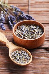Lavender flowers in bowl and spoon on brown table