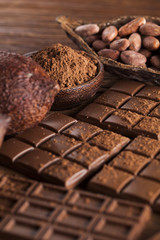 Dark homemade chocolate bars and cocoa pod on wooden