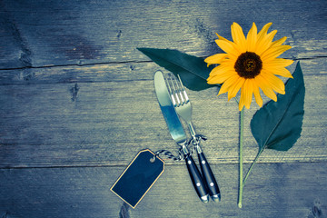 Besteck und Sonnenblume auf einem alten Tisch
