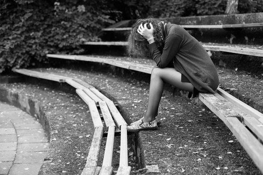 Sad Woman Sitting On The Bench In The Park, Head In The Hands, Despair Pose, Black And White