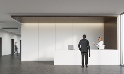 Fototapeta premium Rear view of man talking with receptionist
