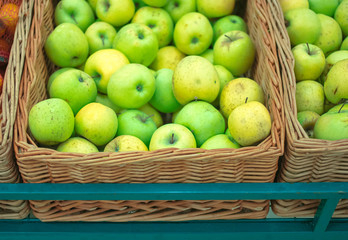 Many green apples in wicker box in grocery store