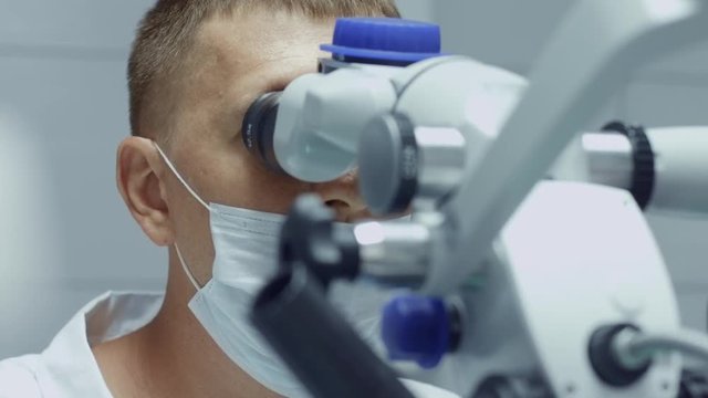 Male dentist working with microscope at modern dentist clinic