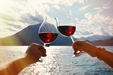 Wineglasses in the hands against lake Como, Italy