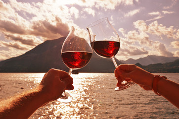 Wineglasses in the hands against lake Como, Italy