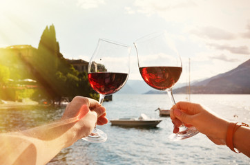 Wineglasses in the hands against lake Como, Italy