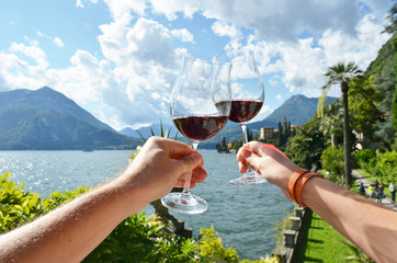 Wineglasses in the hands against lake Como, Italy