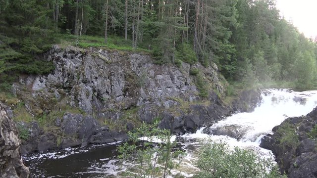 Waterfall on the rocks in wild North nature. High Grand and powerful waterfall "Kivach" the beautiful forests of Karelia. Northern rivers on the rocky ledges.