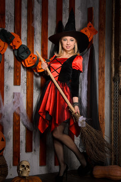 young attractive witch in costume with broom