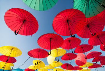 Fototapeta na wymiar colorful yellow, red, blue and green umbrellas under the beautiful cloudy sky